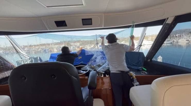 Two installers tinting yacht bridge windows