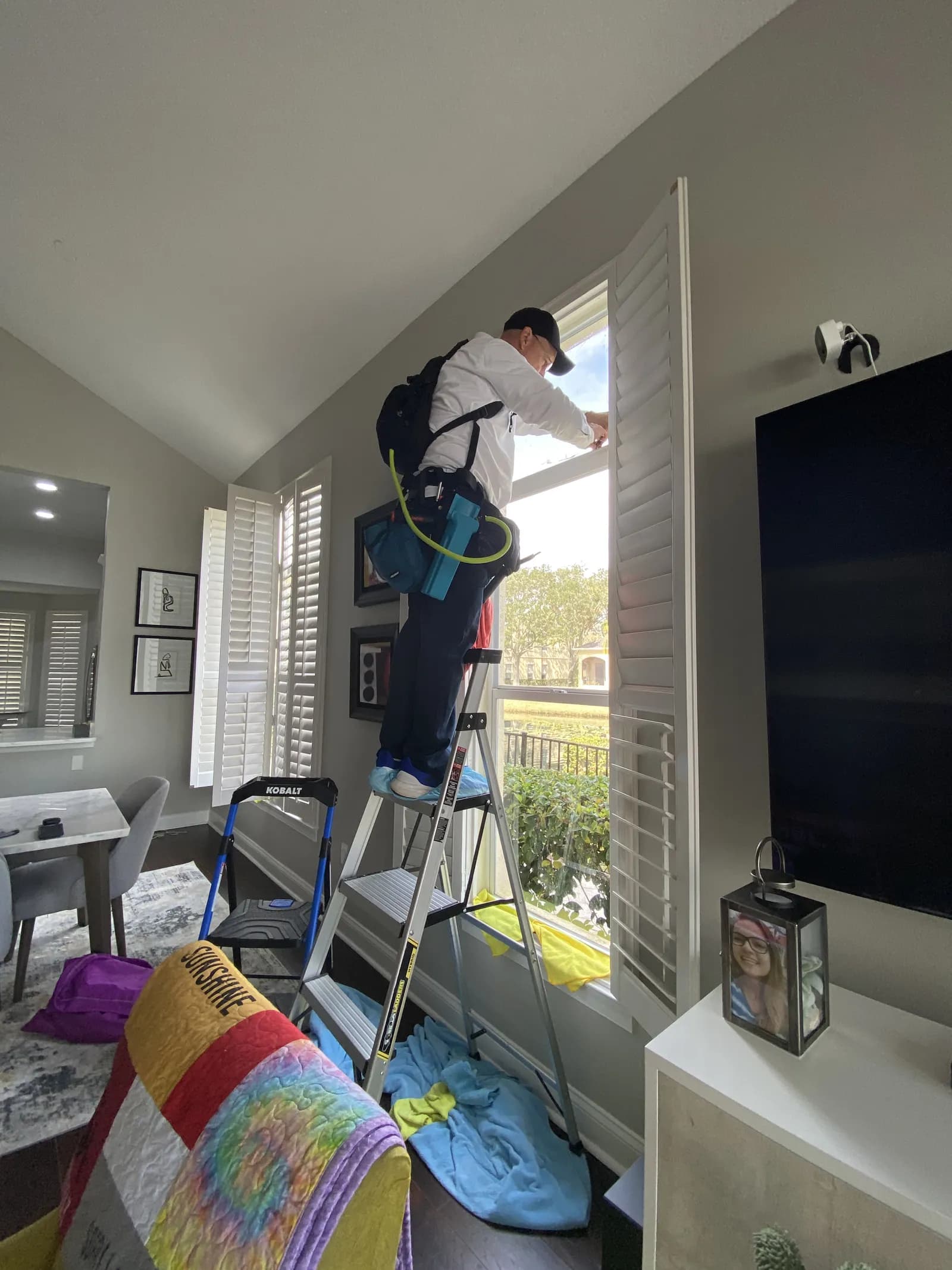 Professional installer on ladder in residential living room